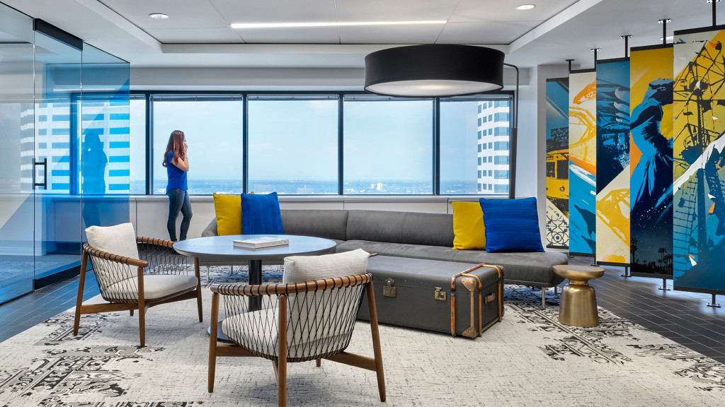 A person standing in a room with a couch and chairs.
